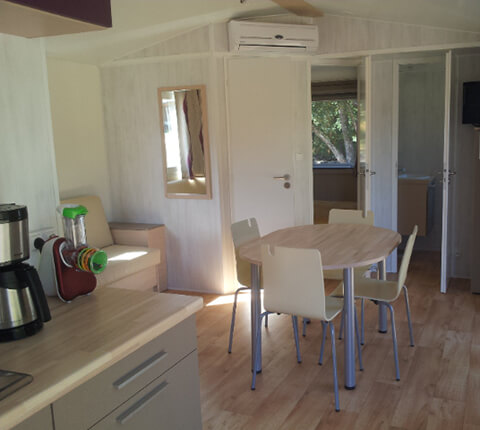 Vue cuisine et coin repas du mobil-home grand large, en location au camping du Lac en Dordogne dans le Périgord vert